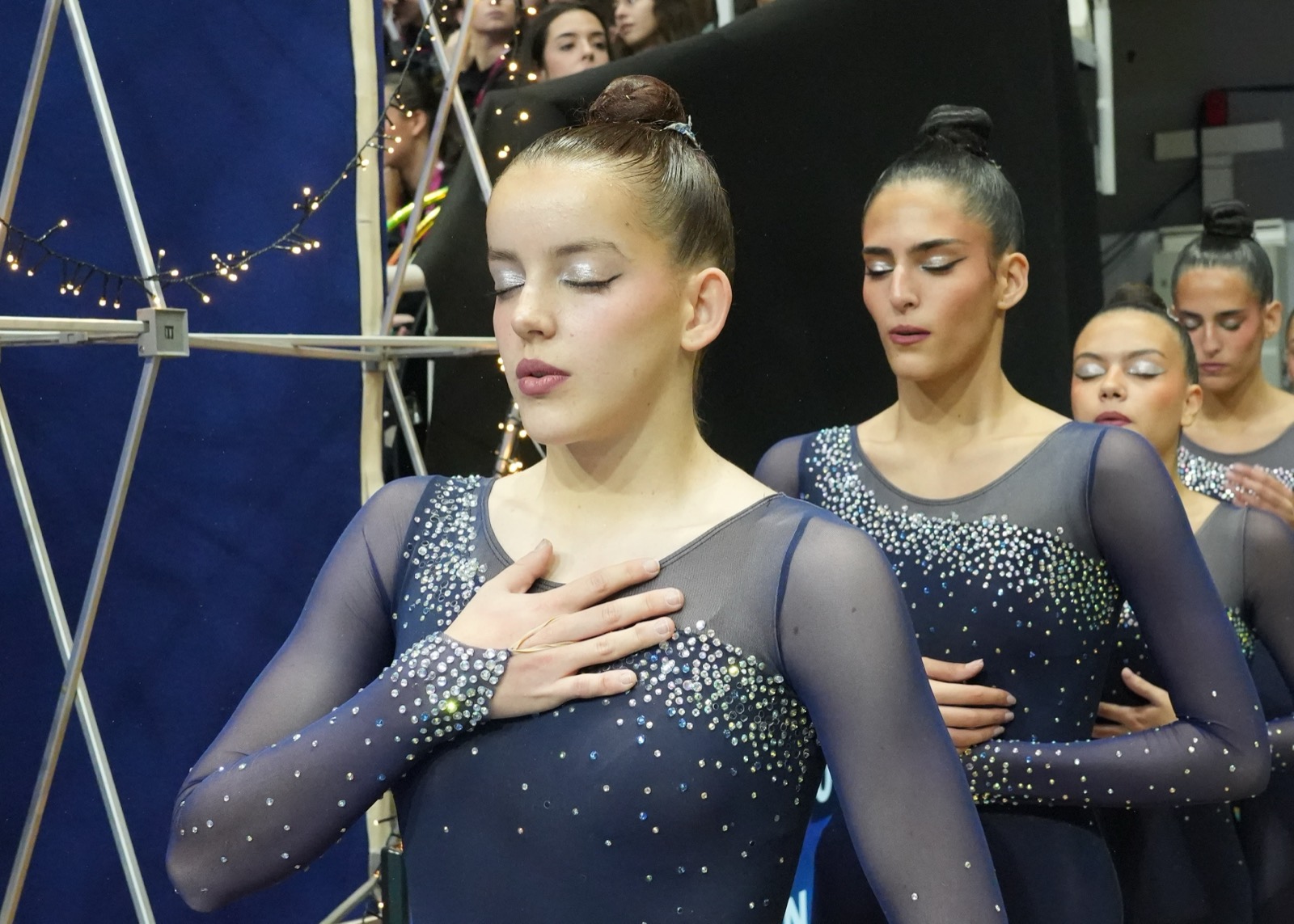 Gimnasta emocionada con la mano en el pecho junto a sus compañeras